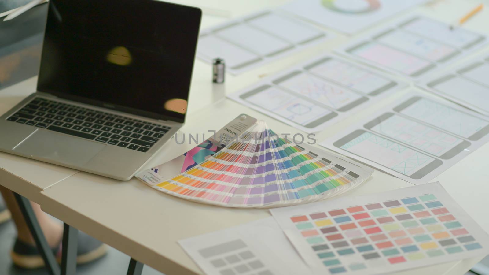 Laptops with color charts and equipment on the desk for the UX team to design apps in a modern office.