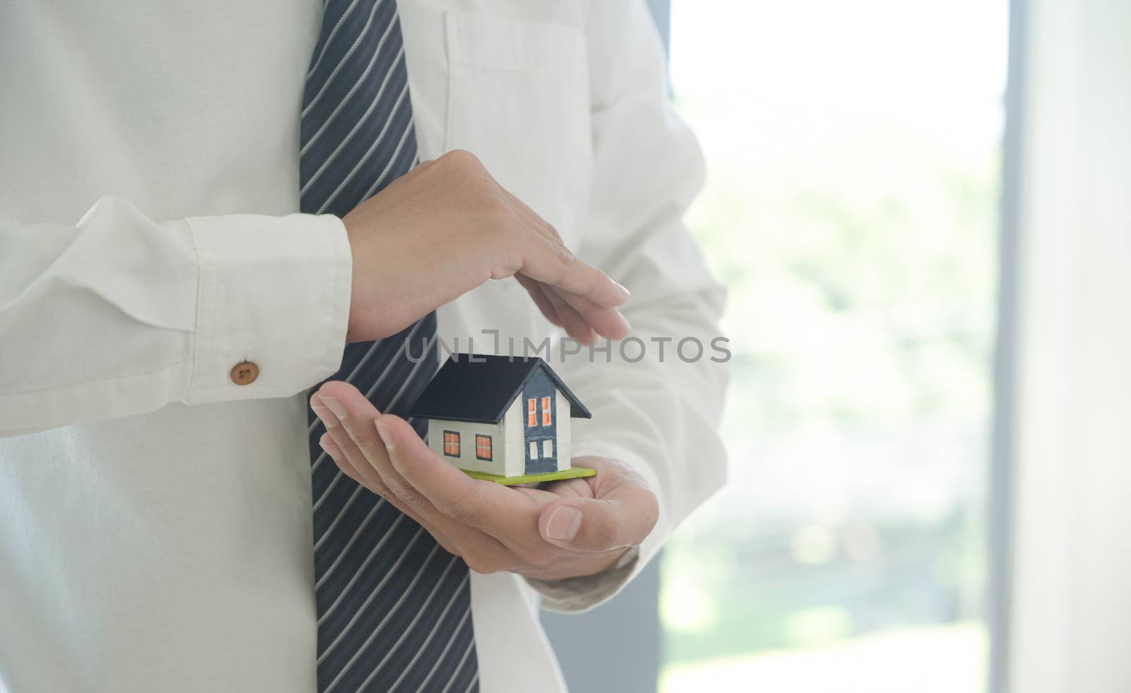 Property insurance concept: Insurance agent holds a house model in hand showing the symbol of home insurance.
