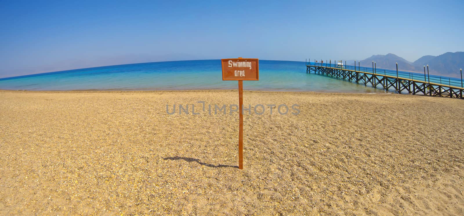 Panoramic view from a tropical beach with swimming area sign