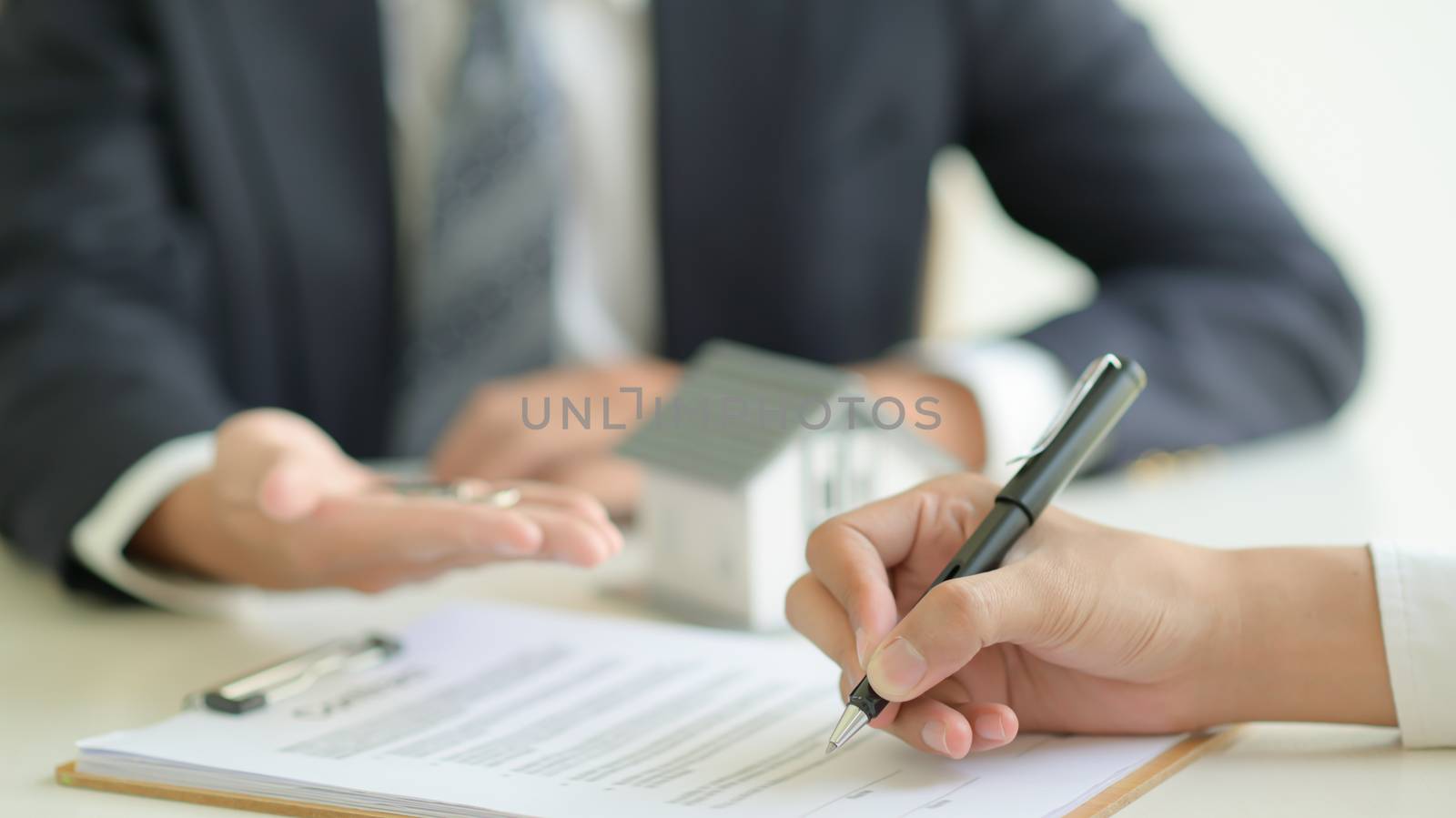Customer signs a home loan contract with a bank official. by poungsaed