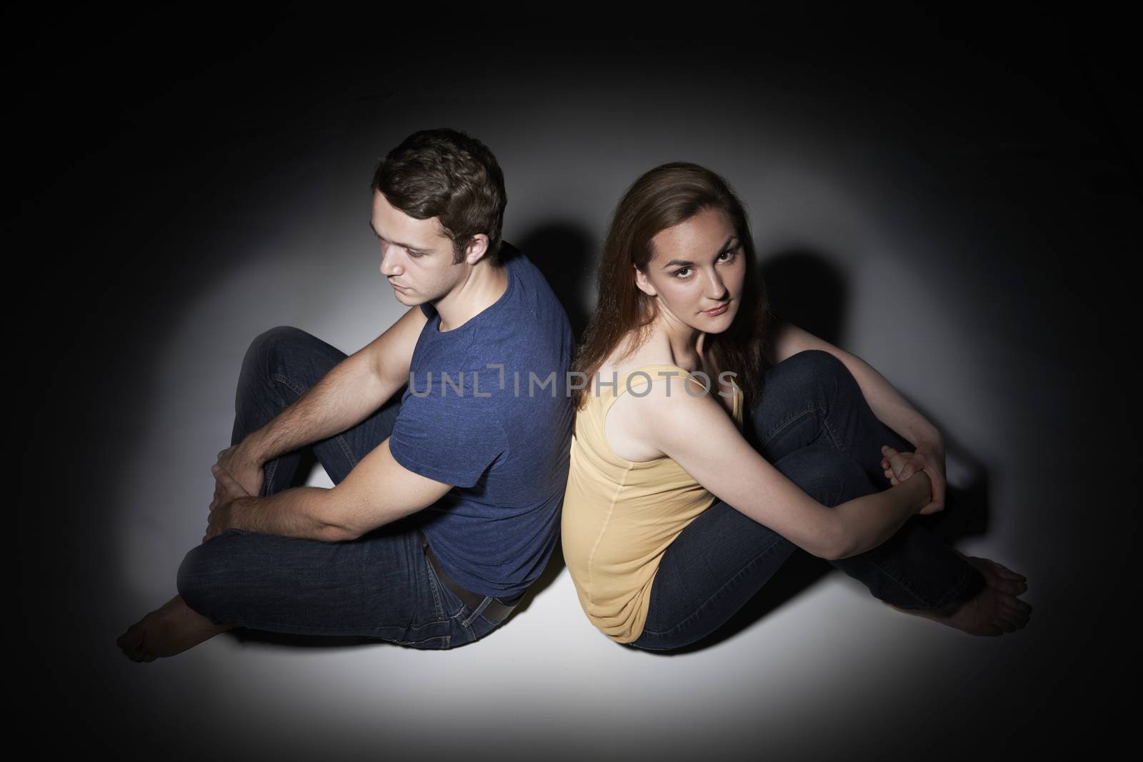 Unhappy Young Couple Sitting In Pool Of Light