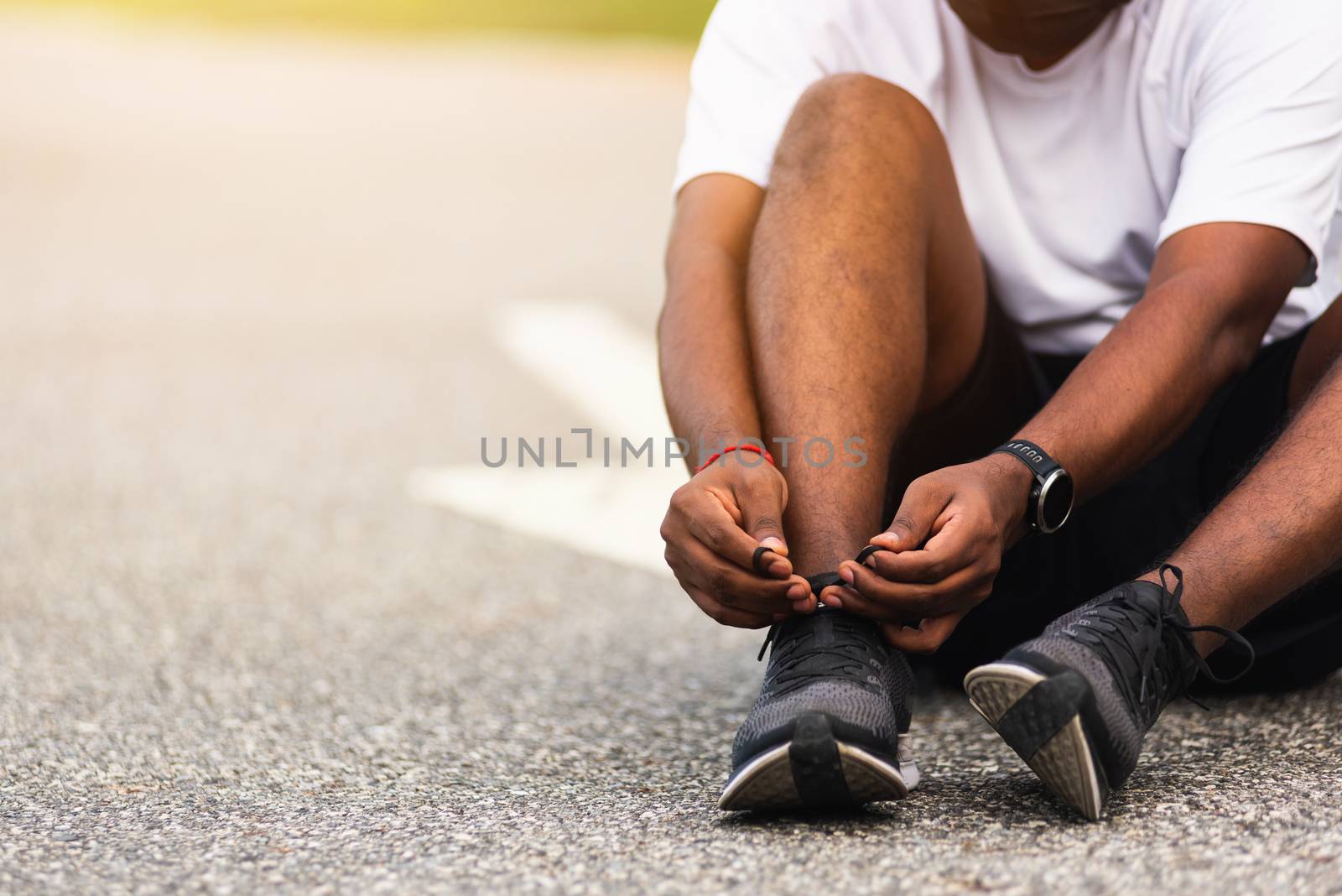 Close up Asian sport runner black man wear watch sitting he trying shoelace running shoes getting ready for jogging and run outdoor street health park with copy space, healthy exercise workout concept