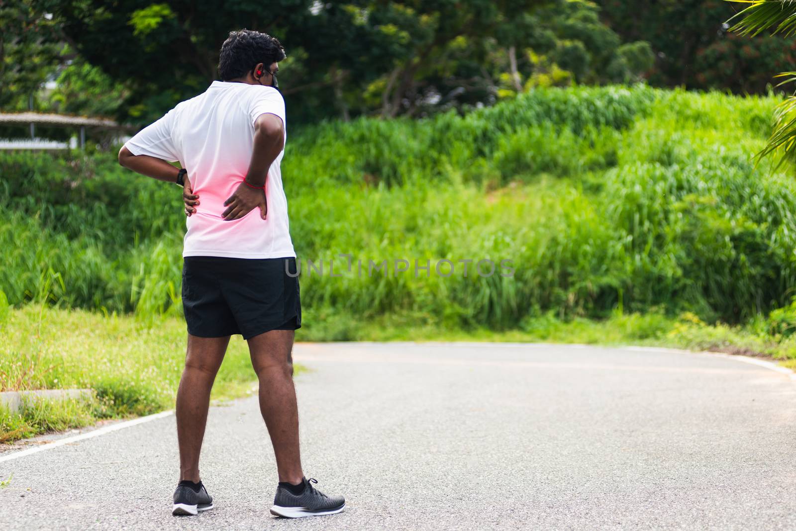 Close up Asian young sport runner black man wear watch feel pain on his spine low back and hip while running at the outdoor street health park, healthy exercise Injury from workout concept