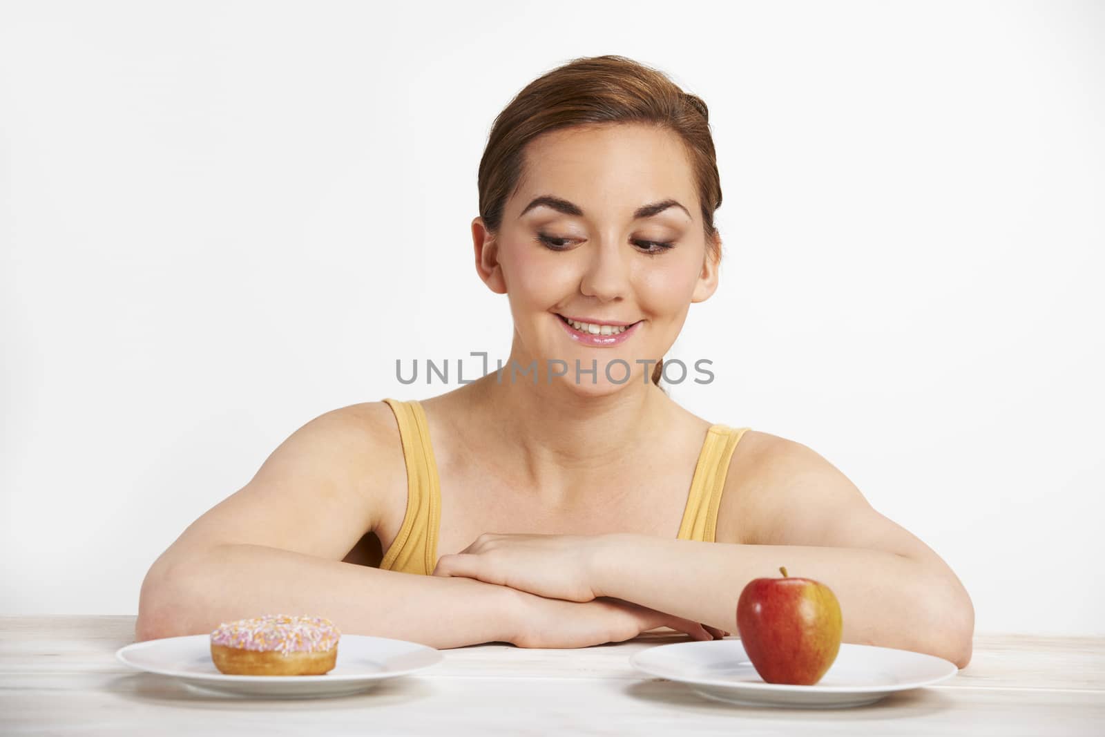 Young Woman Choosing Between Doughnut And Cake For Snack