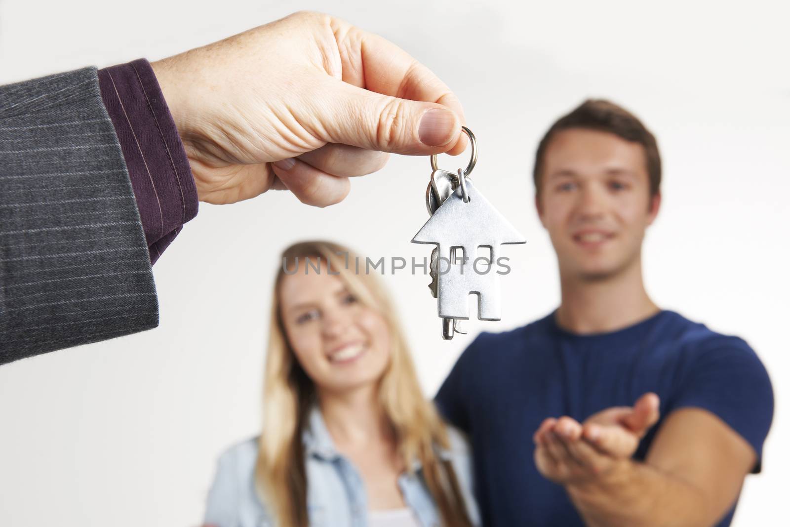 Estate Agent Handing Over House Keys To Young Couple