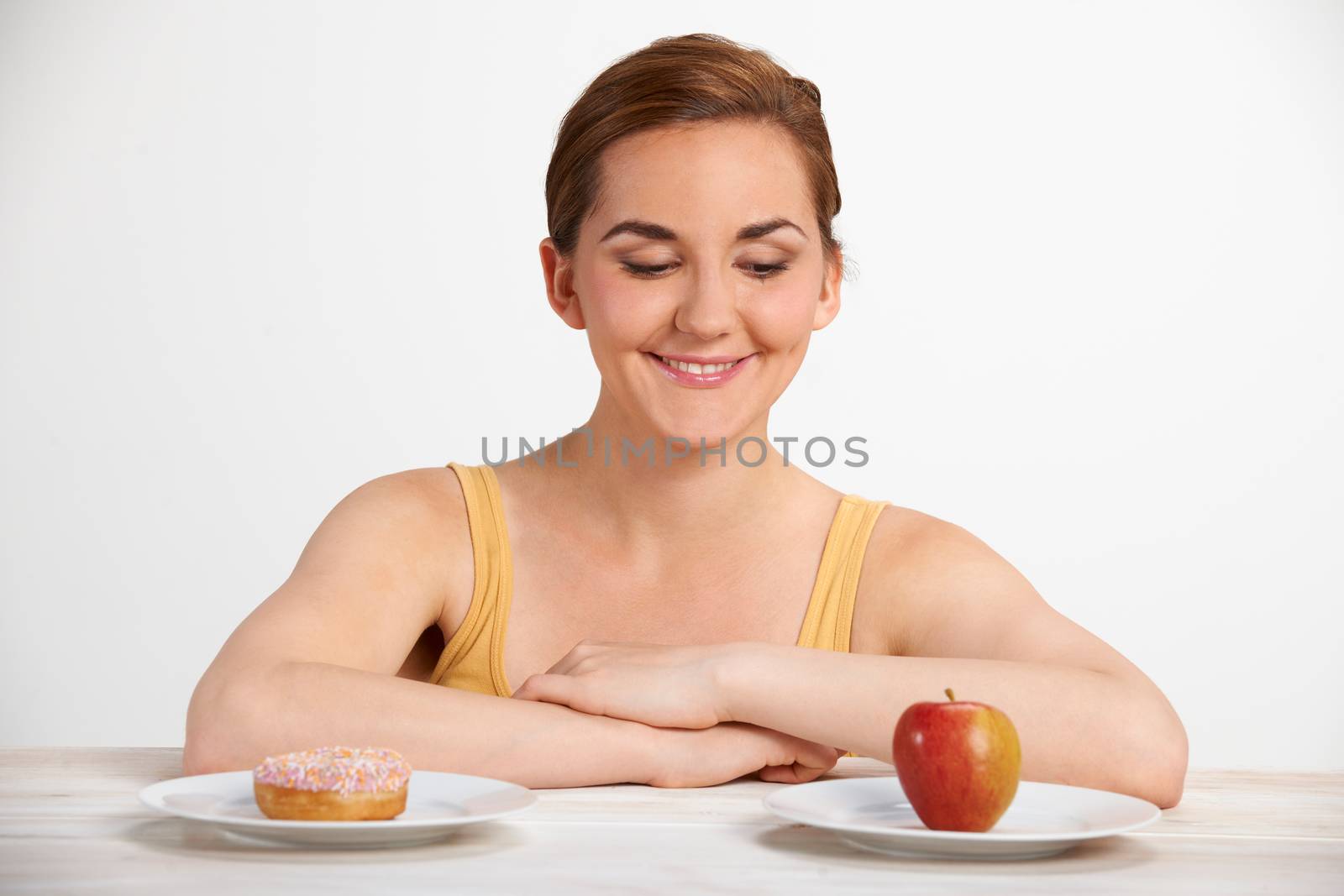 Young Woman Choosing Between Doughnut And Cake For Snack by HWS