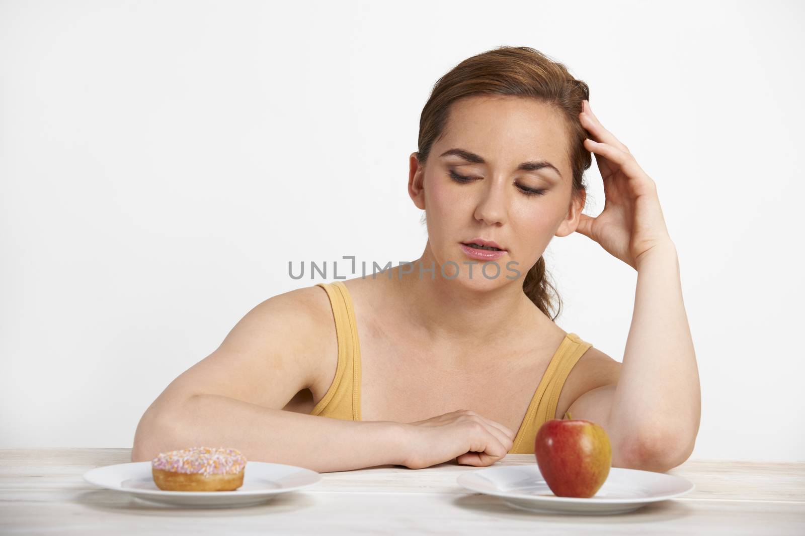 Woman Choosing Between Apple And Doughnut For Snack by HWS