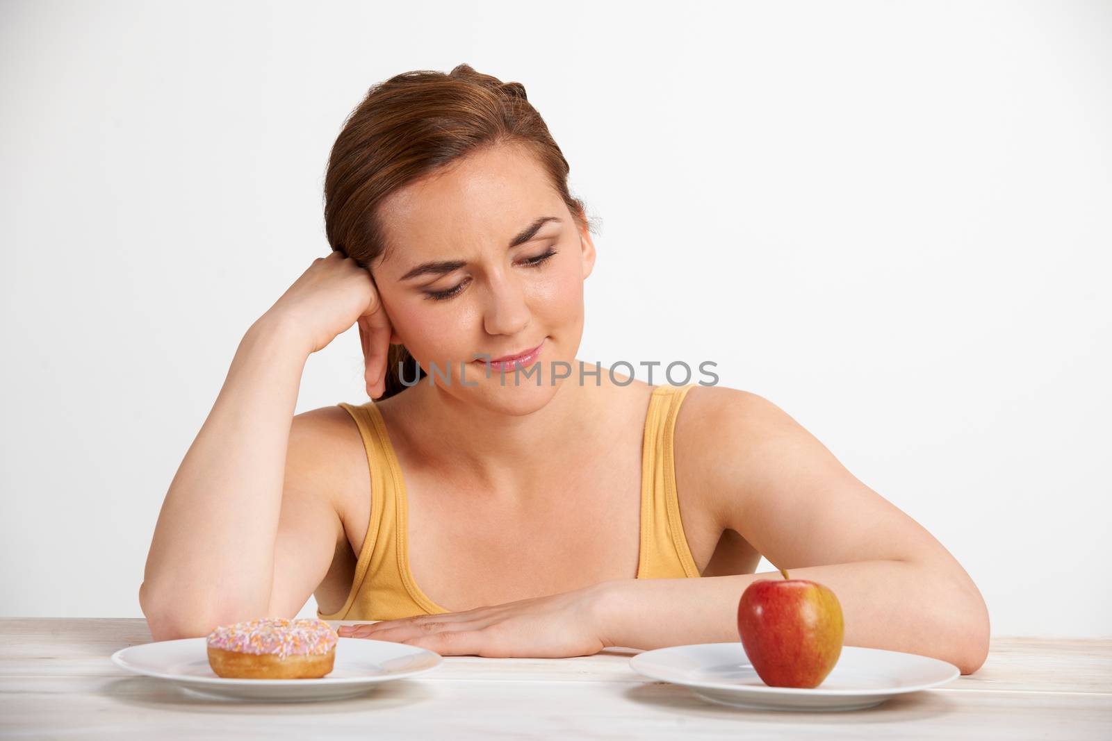 Woman Choosing Between Apple And Doughnut For Snack