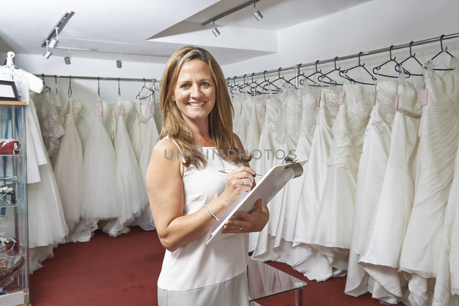 Portrait Of Female Bridal Store Owner With Wedding Dresses