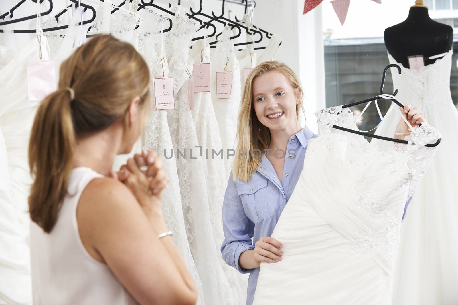 Mother Helping Daughter To Choose Dress In Bridal Store