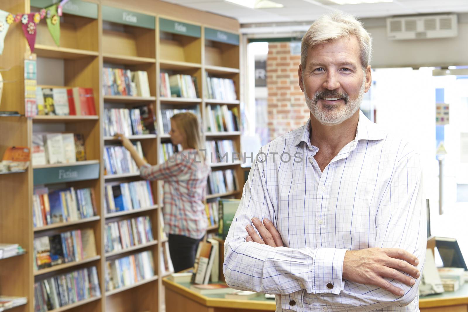 Portrait Of Male Bookstore Owner With Customer In Background by HWS