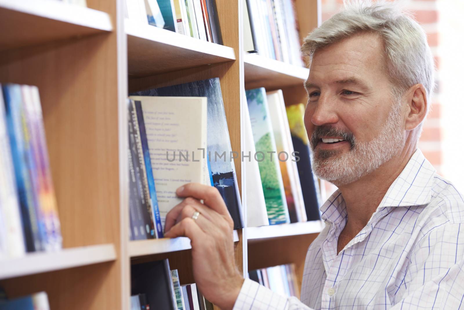 Mature Man Choosing A Book In Bookstore by HWS