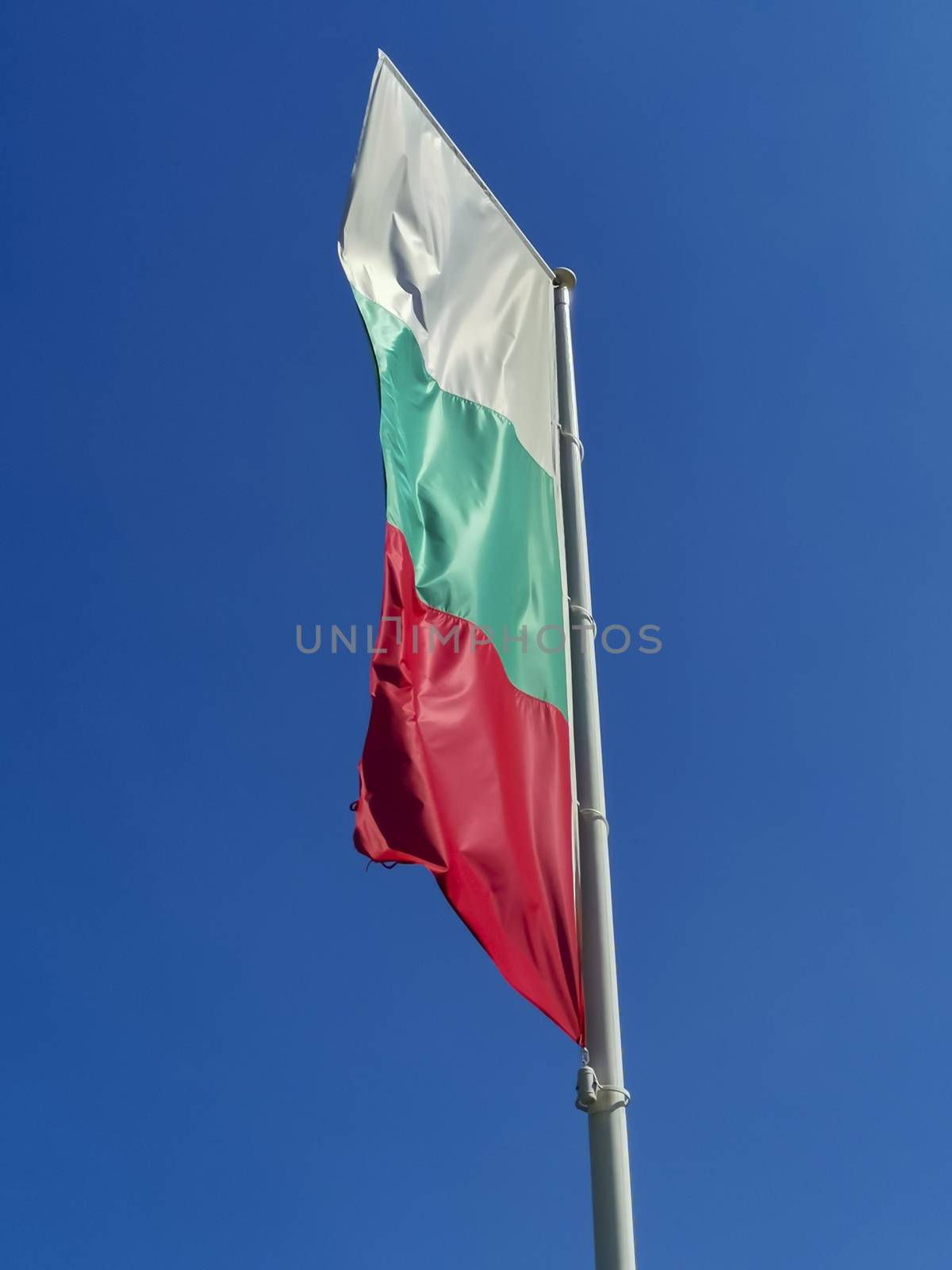 Bulgarian flag waving on blue sky background. The location is Obzor, Bulgaria. Flag of Bulgaria against the clear sky.