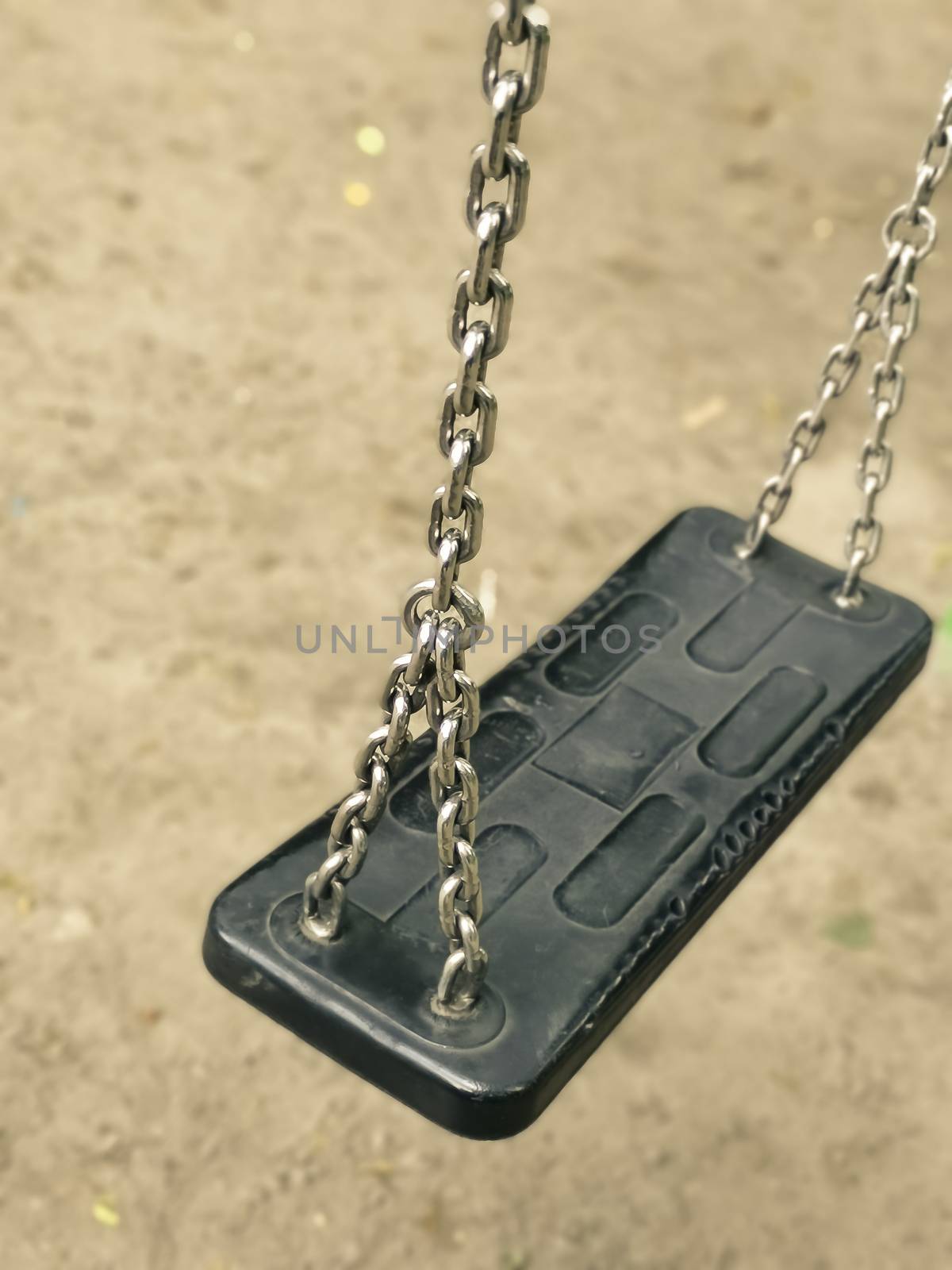 Empty swing on kids playground. vacant chain swing for children in a park on ground background. Close up photo. Corona virus causes empty playgrounds