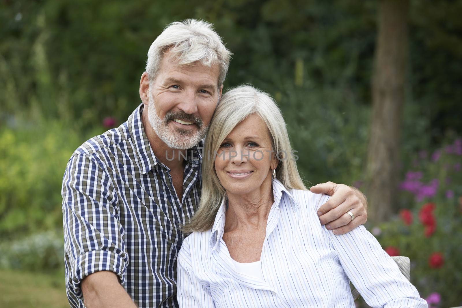 Portrait Of Mature Couple Relaxing In Garden Together by HWS