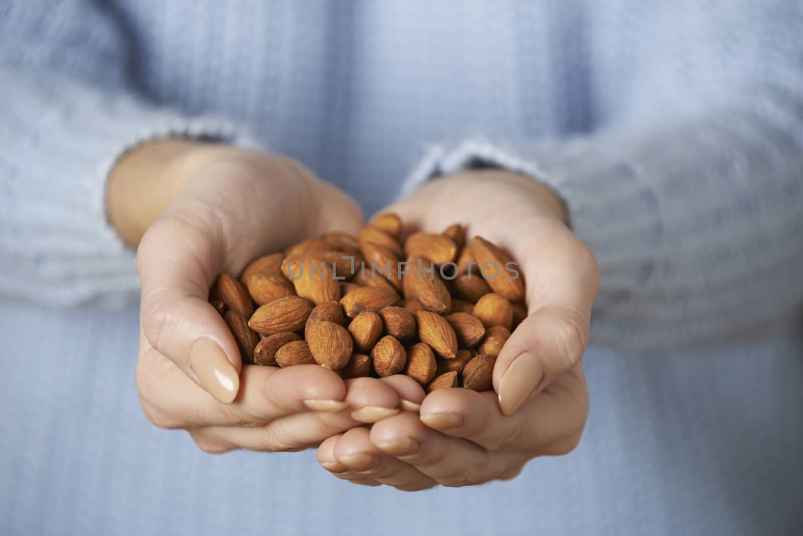 Close Up Of Woman Holding Handful Of Almonds