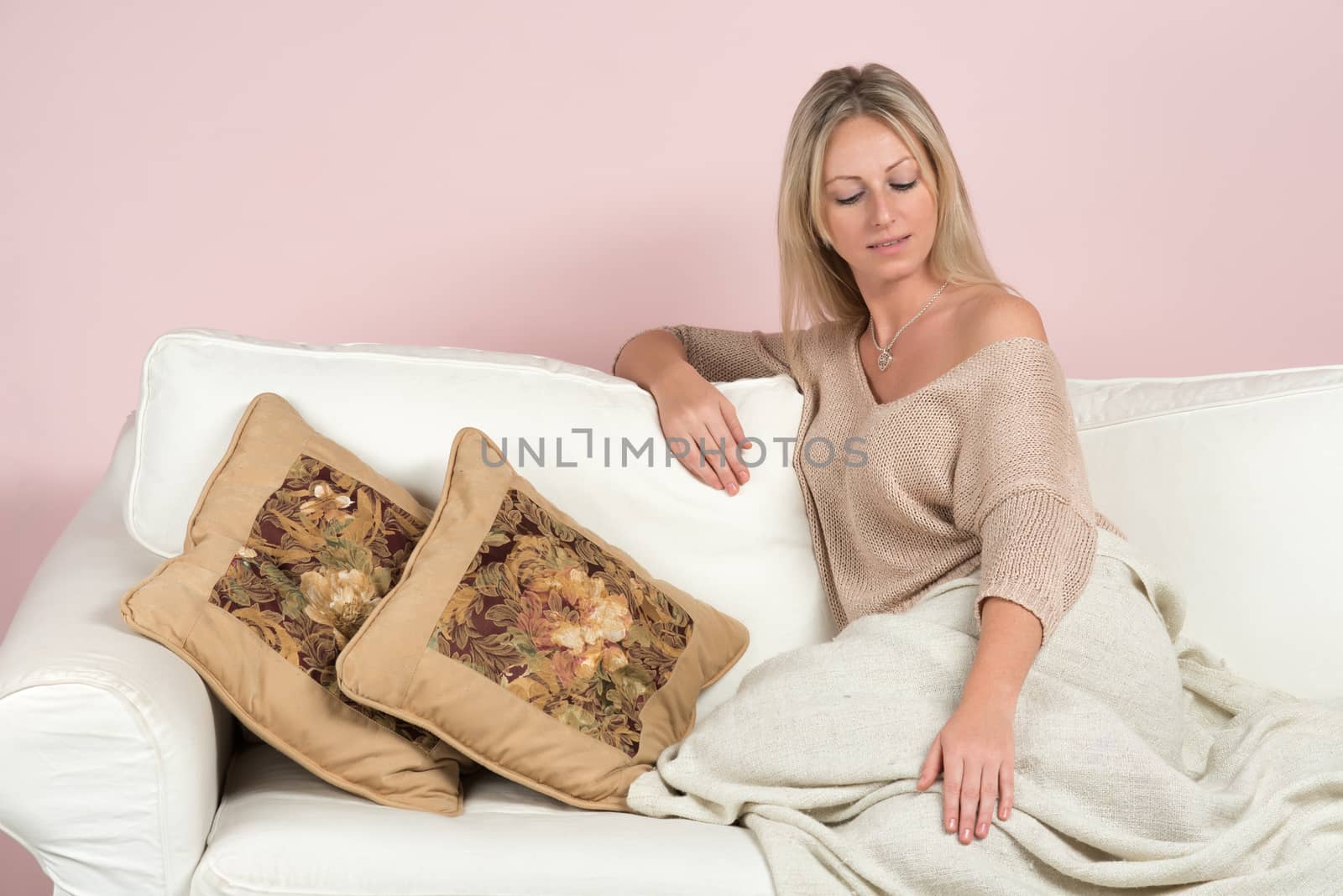 Sensual young woman in a sweater on a sofa with cushions