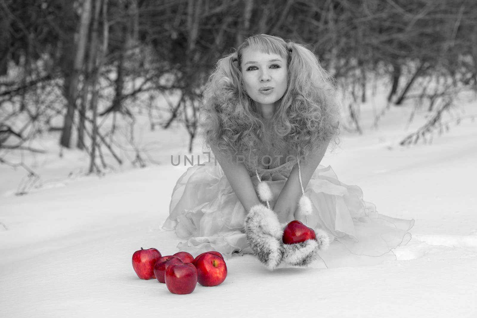 Appealing young Snow Maiden - the grandaughter of Father Frost - in transparent blue dress poses at winter forest with apples