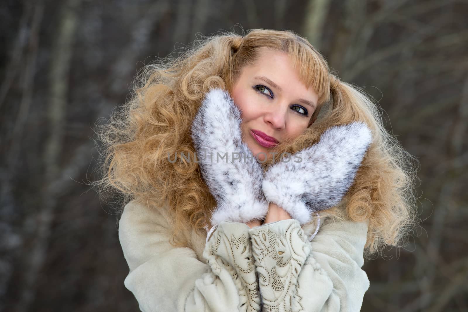 Smiling pretty young woman in a winter forest in a fur coat