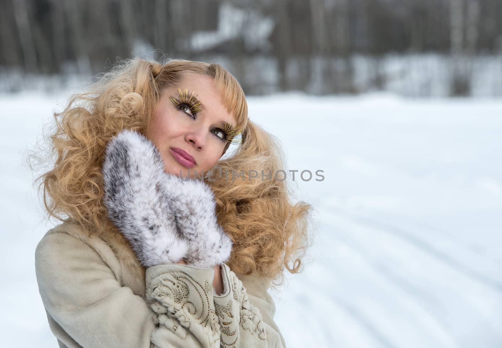 Giddy young woman with exaggerated cilia in a winter field