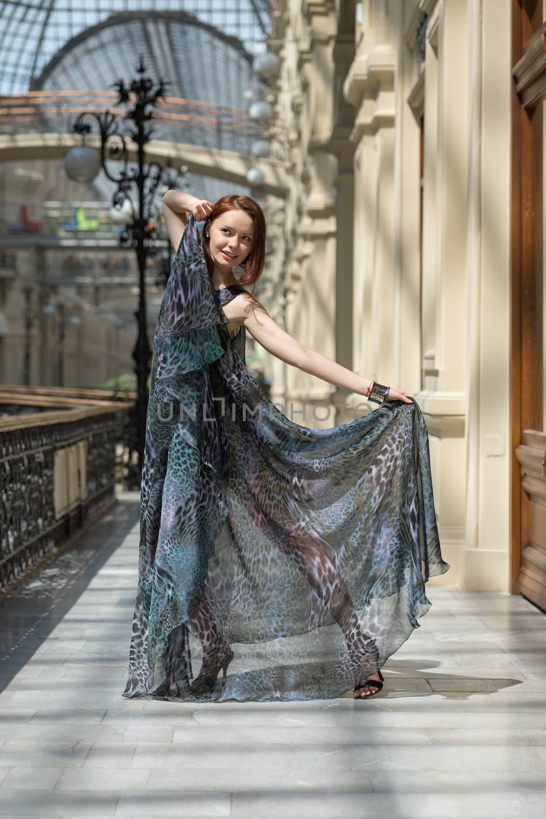 Playful young model demonstrates fashionable gauzy clothing in an aged building under the daylight