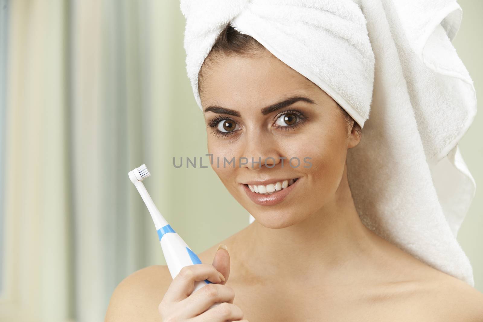 Woman Brushing Teeth With Electric Toothbrush In Bathroom