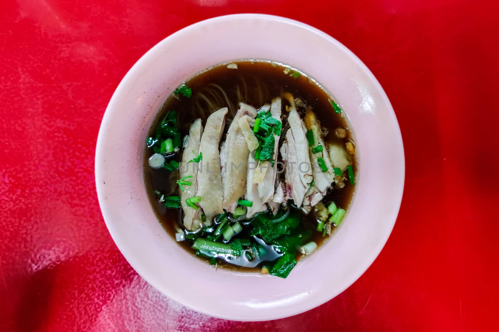 Stewed chicken noodle soup on the red table