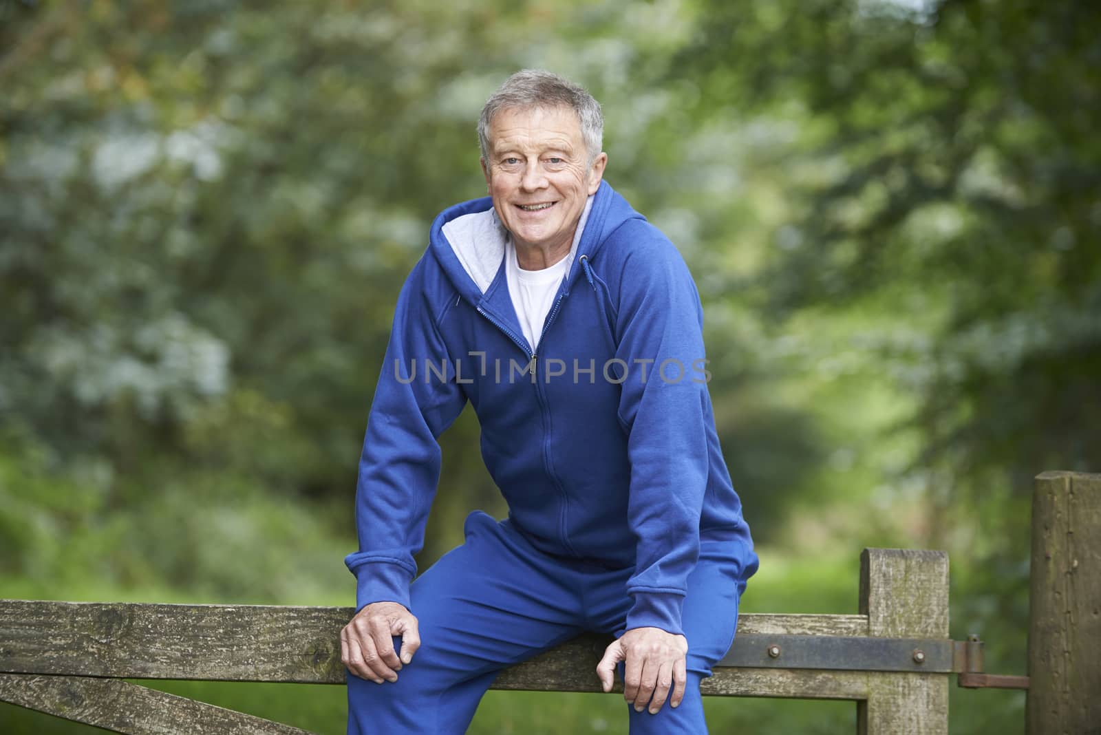 Senior Man Resting On Gate During Exercise In Countryside by HWS