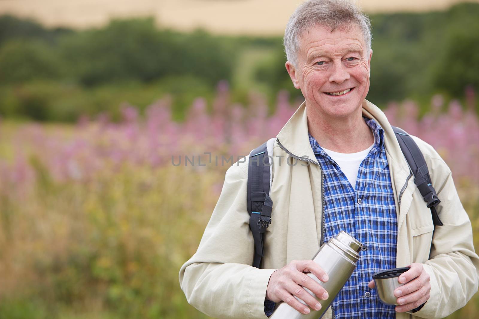 Senior Man Pouring Drink From Flask On Walk