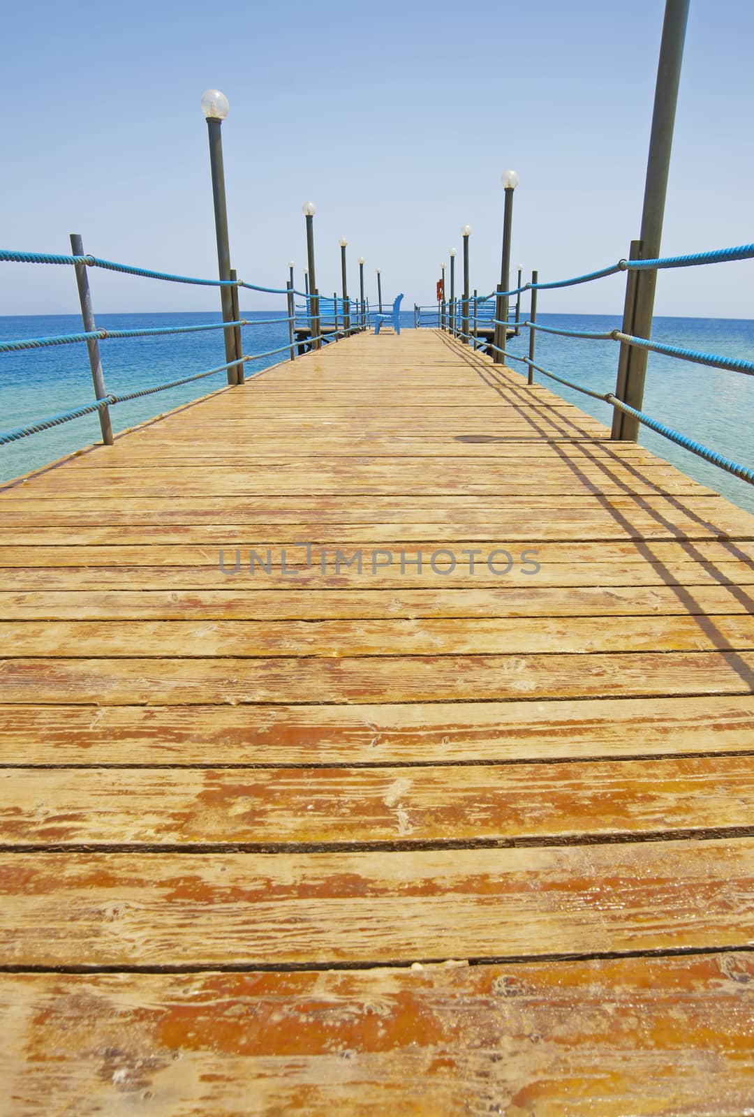 A small wooden jetty going into the sea from a tropical beach