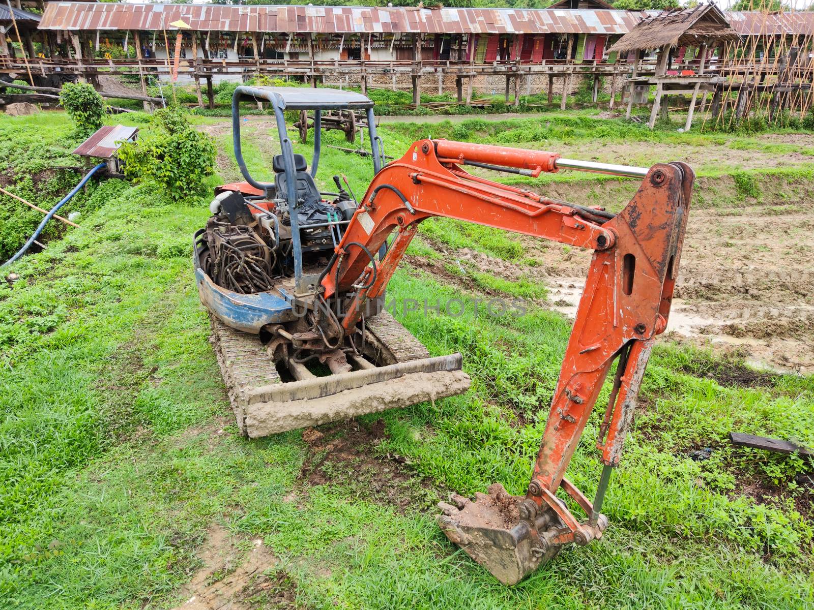 old broken yellow excavator in rice field, Thailand. by tidarattj