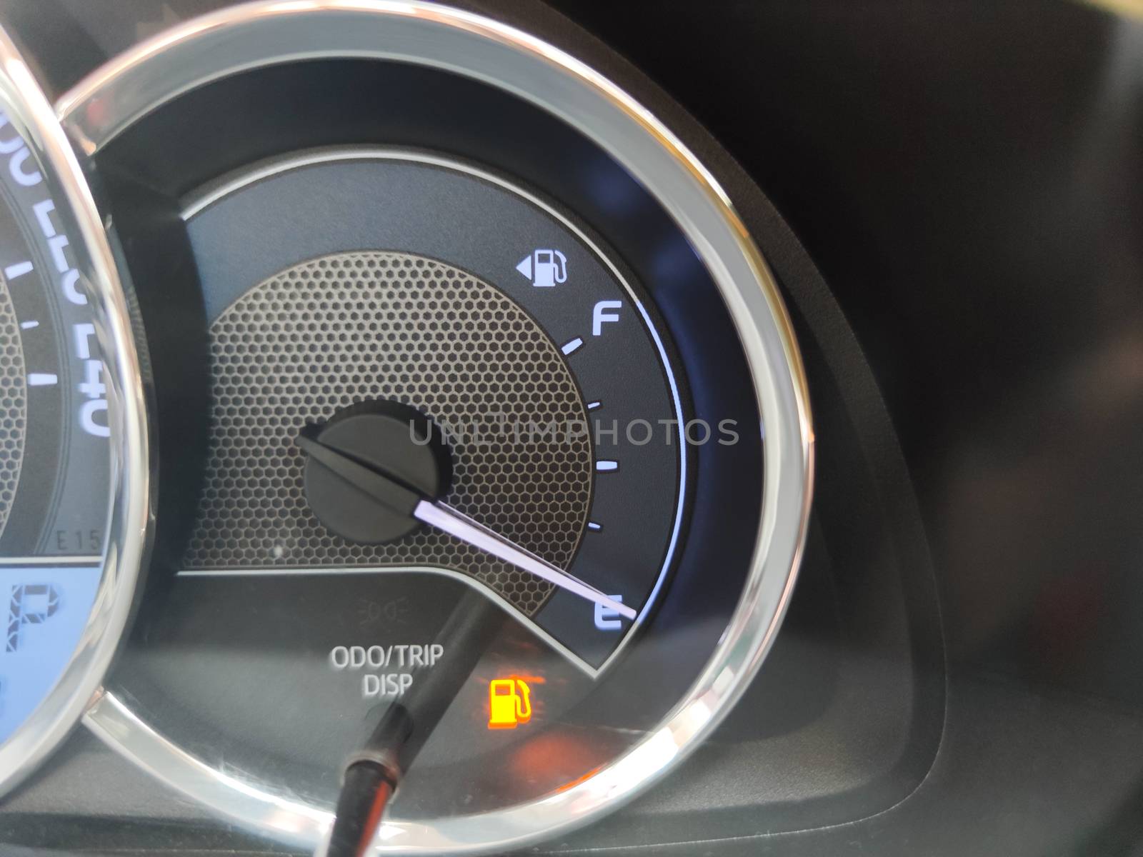 close-up fuel gauge showing empty tank with yellow light glowing