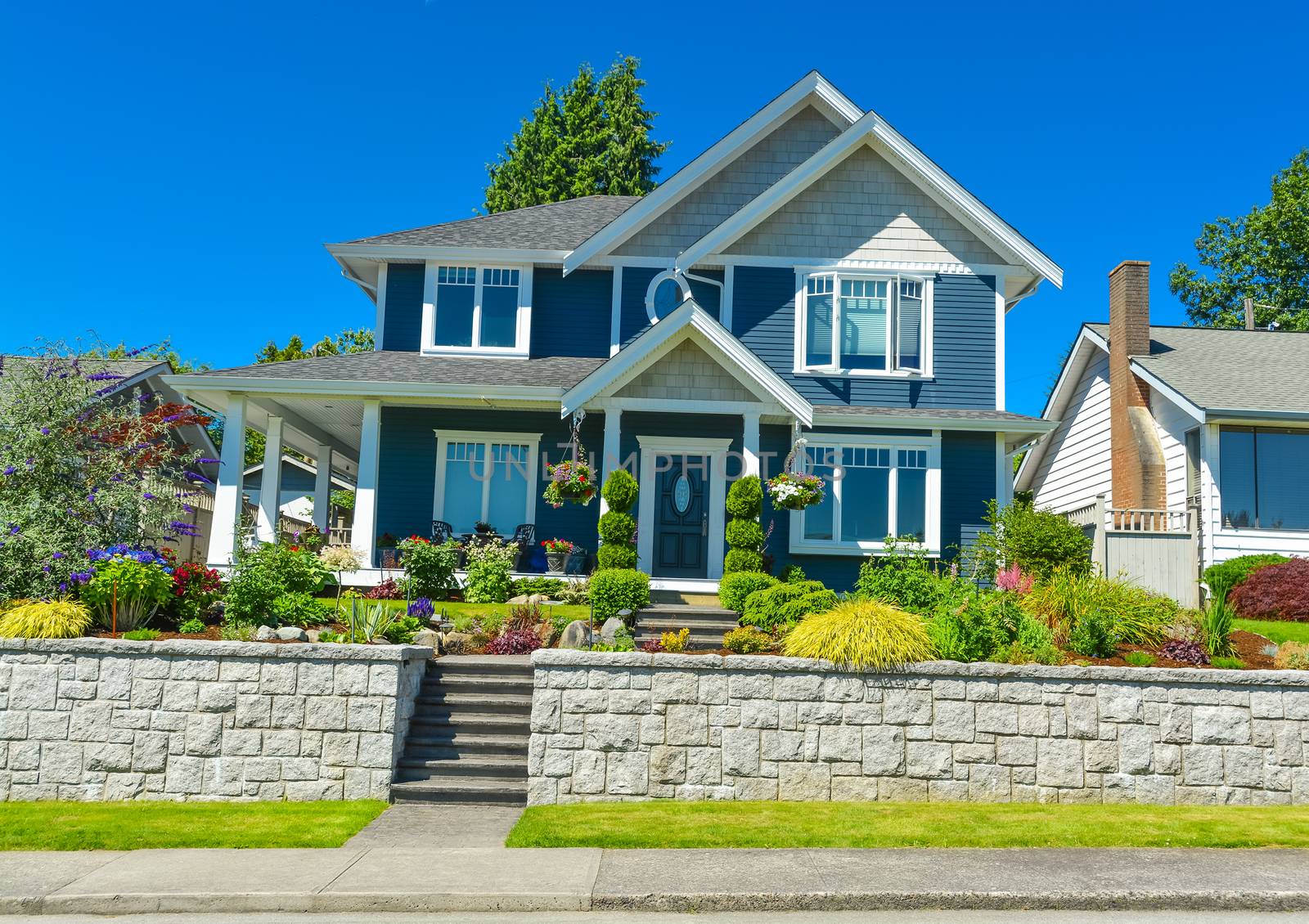 Luxury family house with landscaped front yard on land terrace. Family house on blue sky background