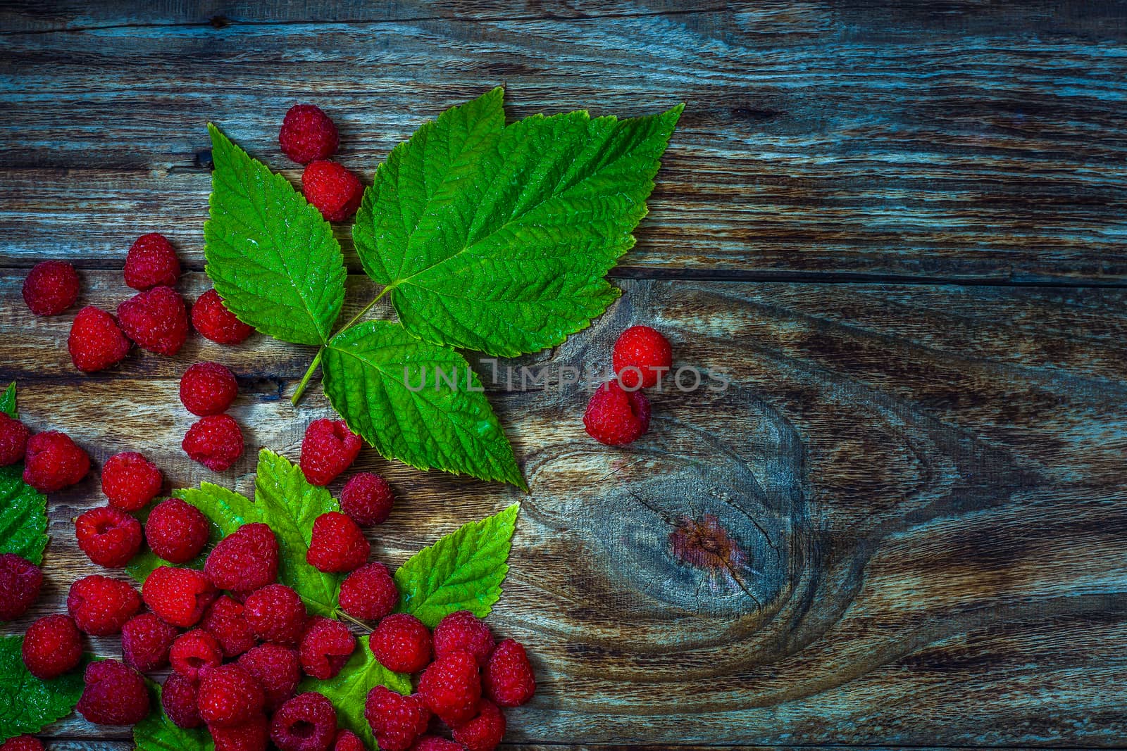 Fresh ripe raspberries close-up on old wooden table. Summer berries background. Top view.