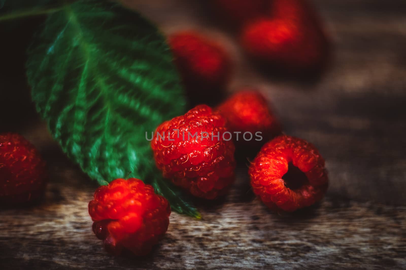 Raspberries close up view. Macro photo food raspberry. Natural ripe organic berries with peduncles, green leaves, top view, flat lay with copy space.