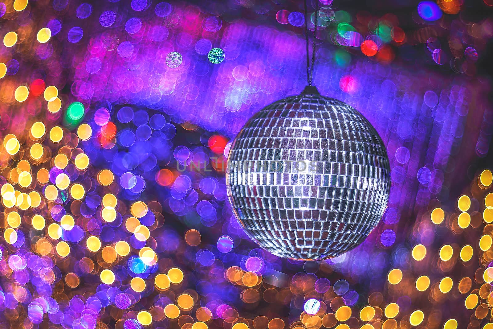 Mirror disco ball on beautiful shiny background with bokeh. Festive abstract image with defocused lights. Disco party. Copy space.