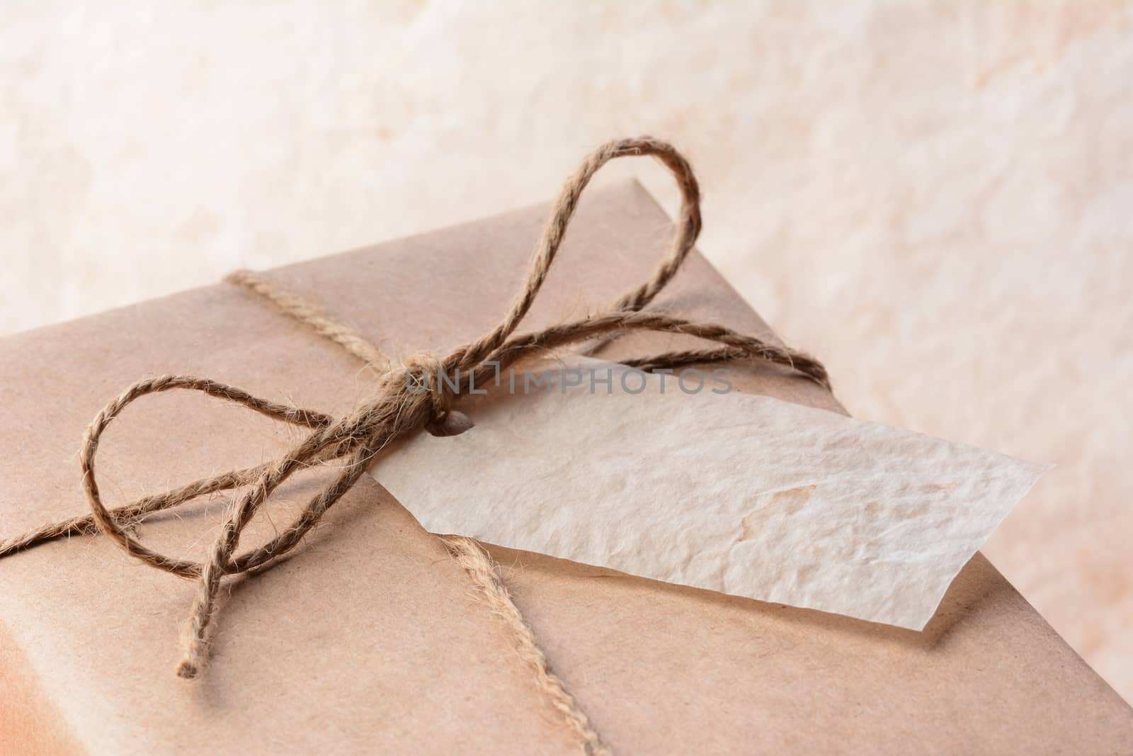 Closeup of a brown eco friendly paper wrapped package with gift tag. Horizontal format with shallow depth of field.