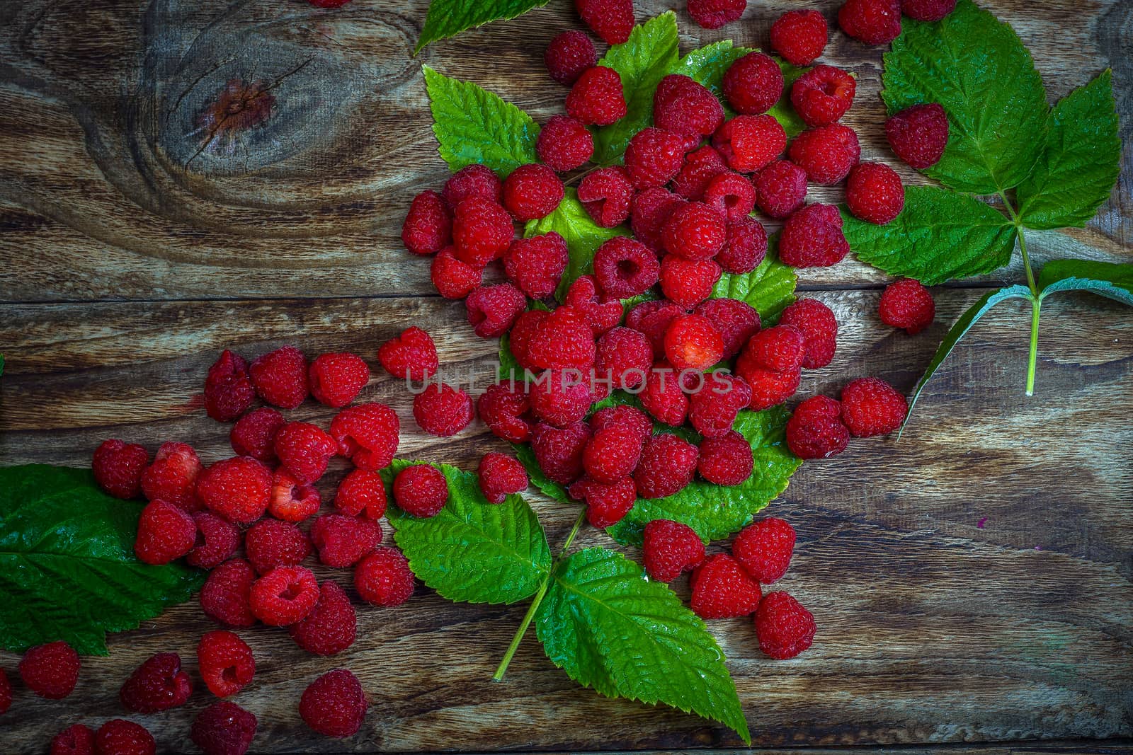 Fresh raspberries background close-up photo. Fresh raspberries on a rustic wooden table. Selective focus.