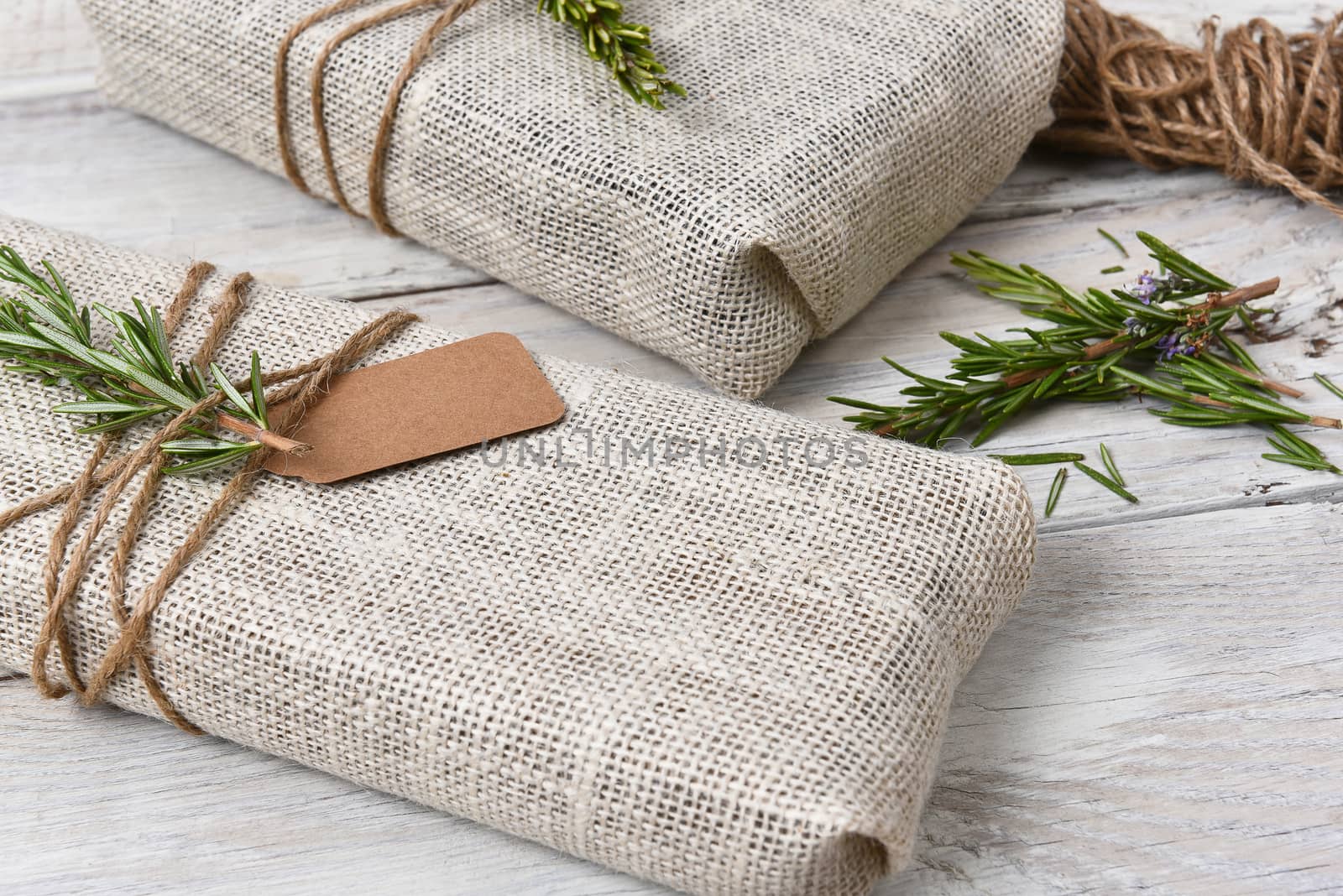 Closeup of two fabric wrapped Christmas presents on a rustic wood table.