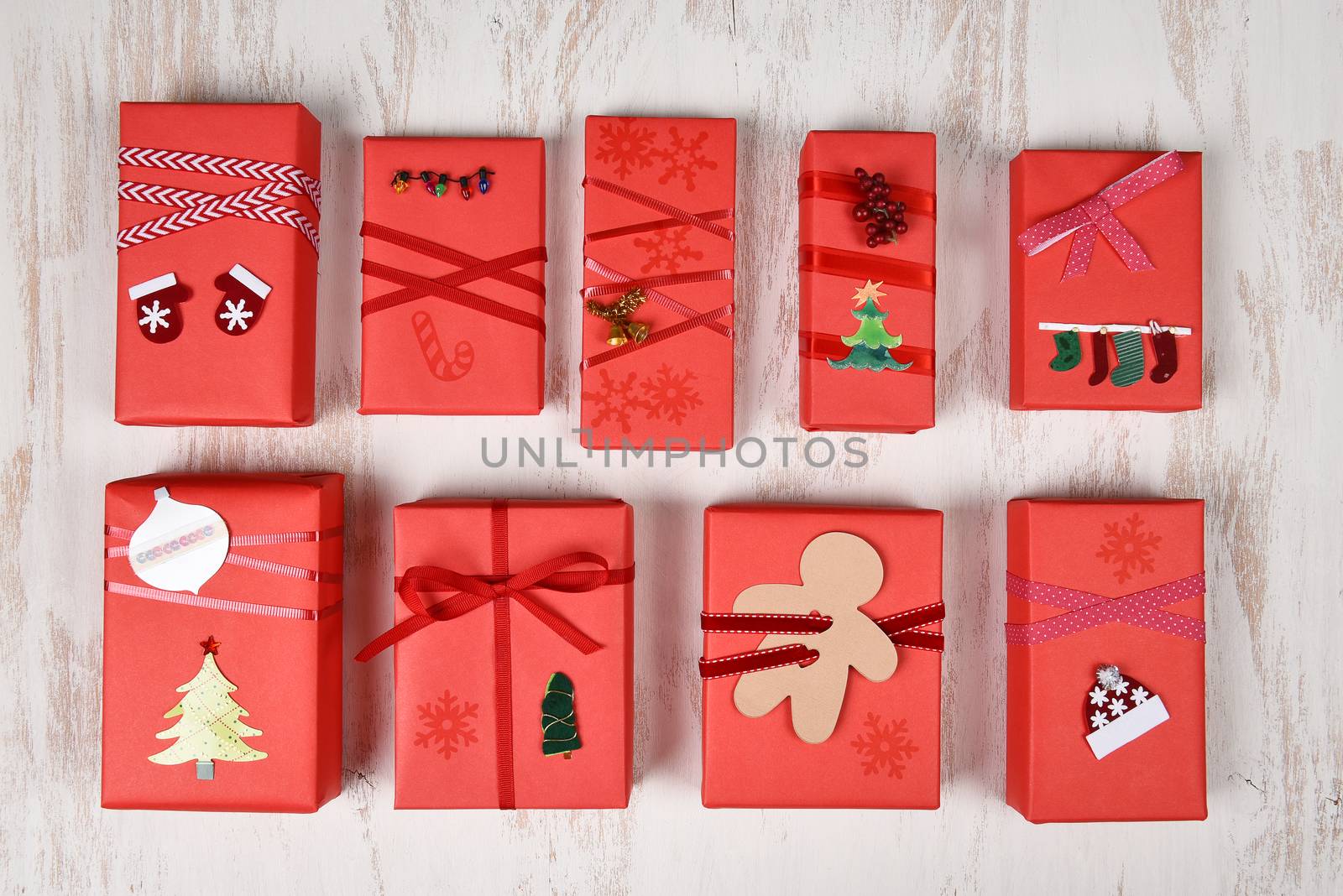 Top view of a group of Christmas presents wrapped in red paper and decorated in various designs.