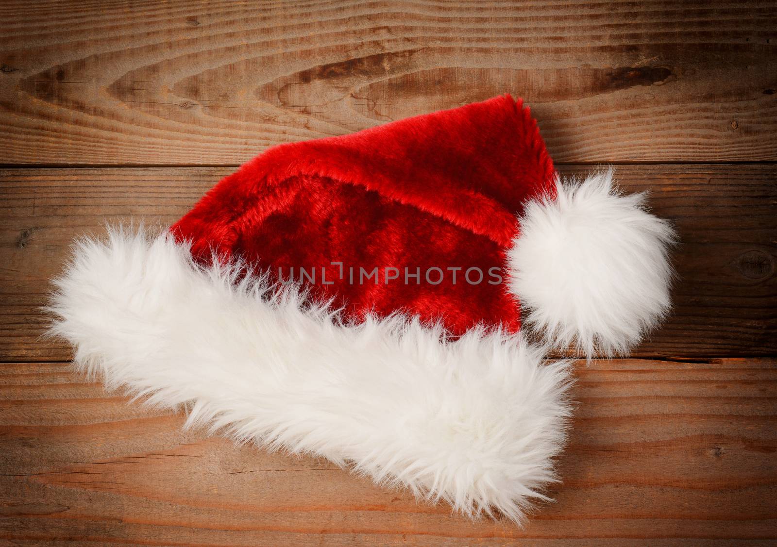 Santa Claus Hat on a rustic wooden floor with an instagram retro look. High angle view with vignette.