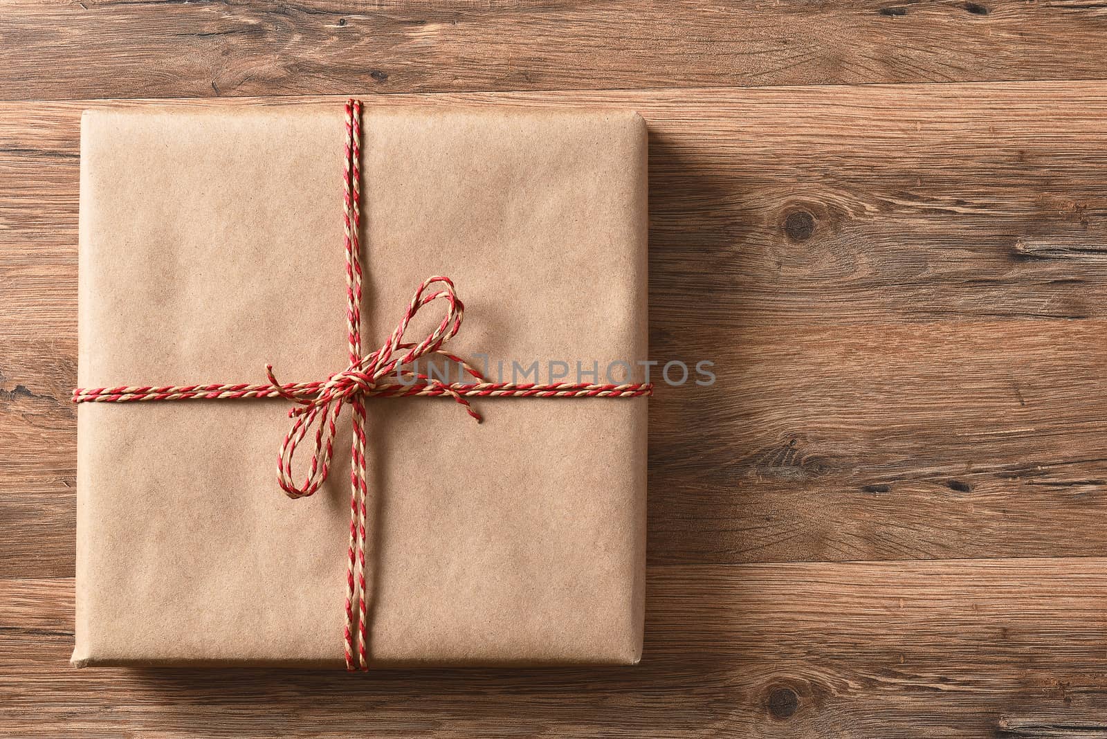 High angle view of a plain paper wrapped present on a rustic wood table. 