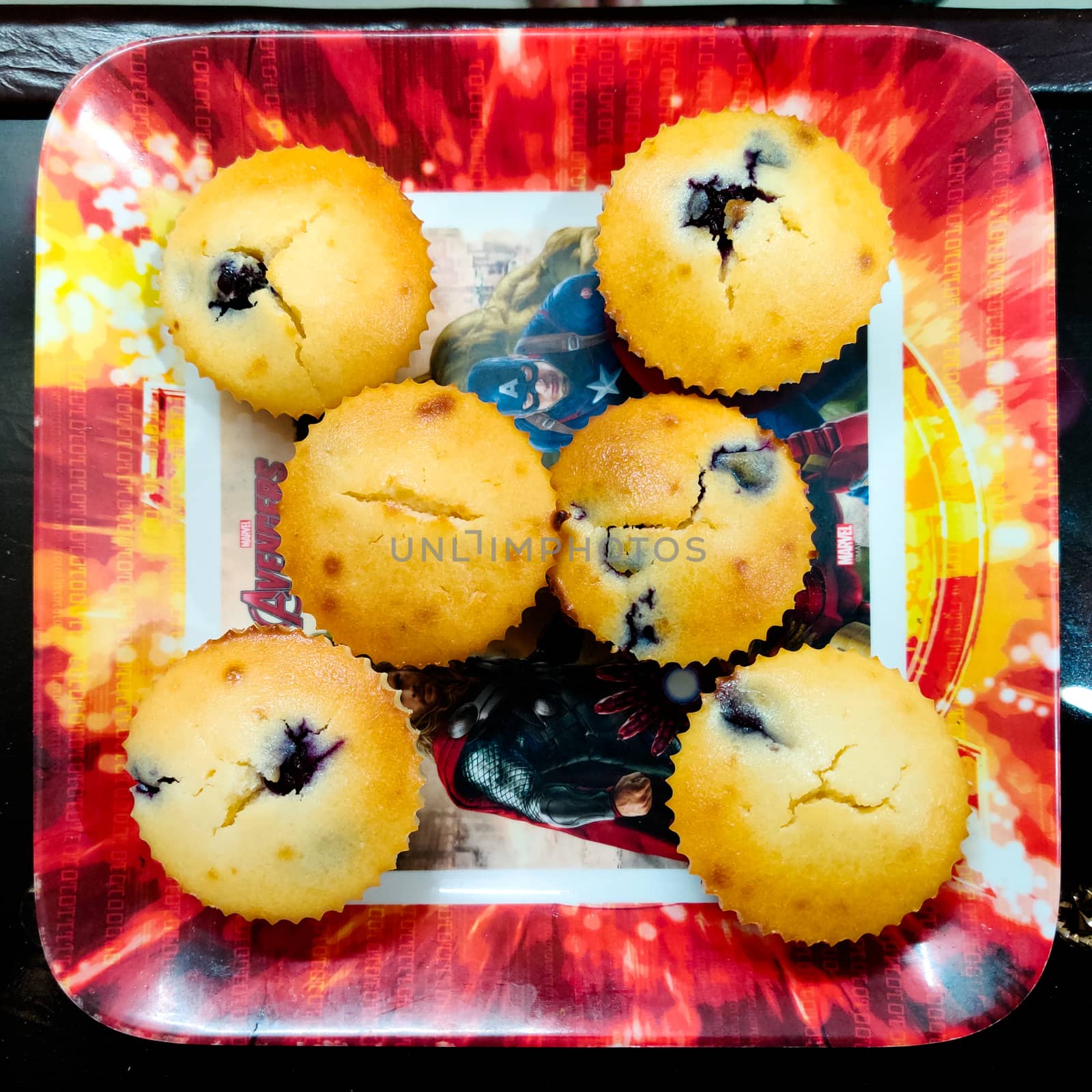 Freshly baked at home muffins in colorful cups placed in a shiny microwave. Shows the renewed interest in cooking due to the coronavirus pandemic lockdown