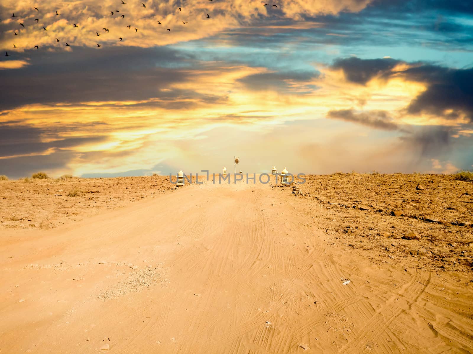 Empty dirt road with barren desert on both sides and blue sky above showing thar desert of rajasthan india.