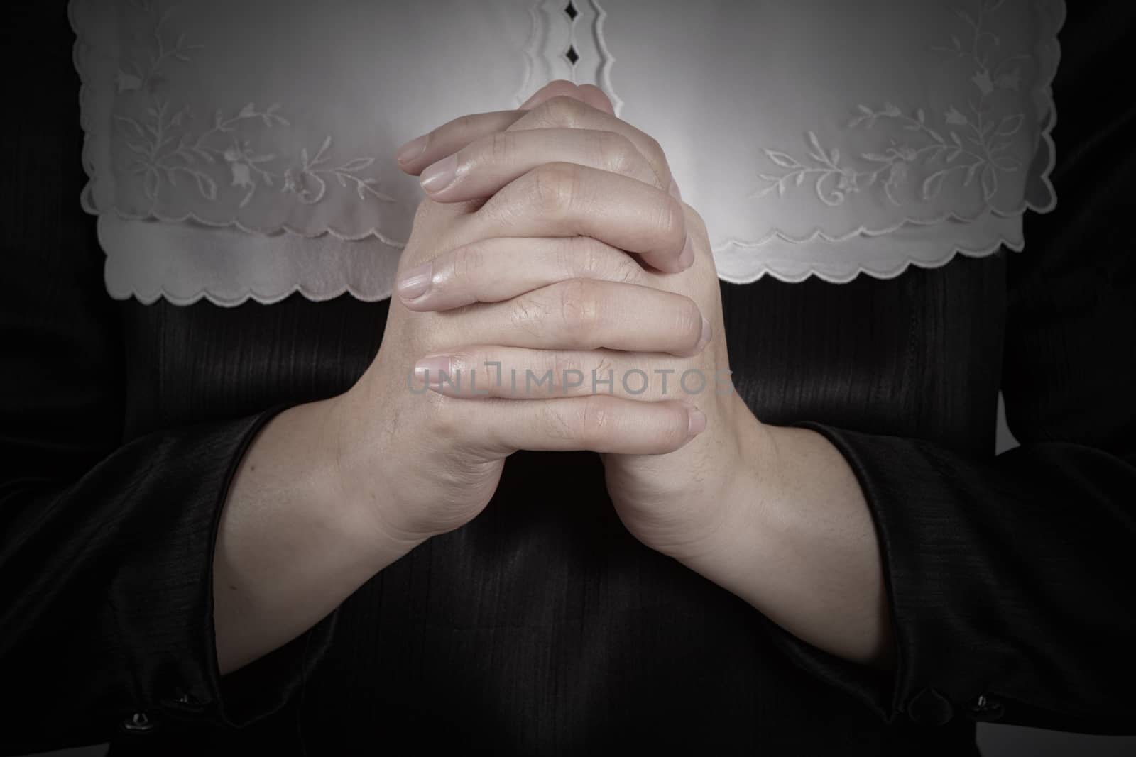 hand of nun praying on black background