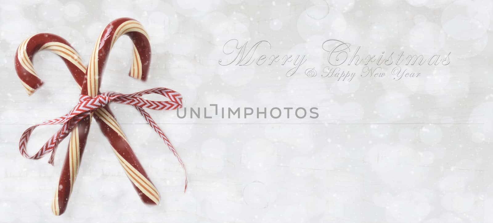 Holiday Candy Canes with Merry Christmas and Happy New Year on a silver bokeh background with snow effect.