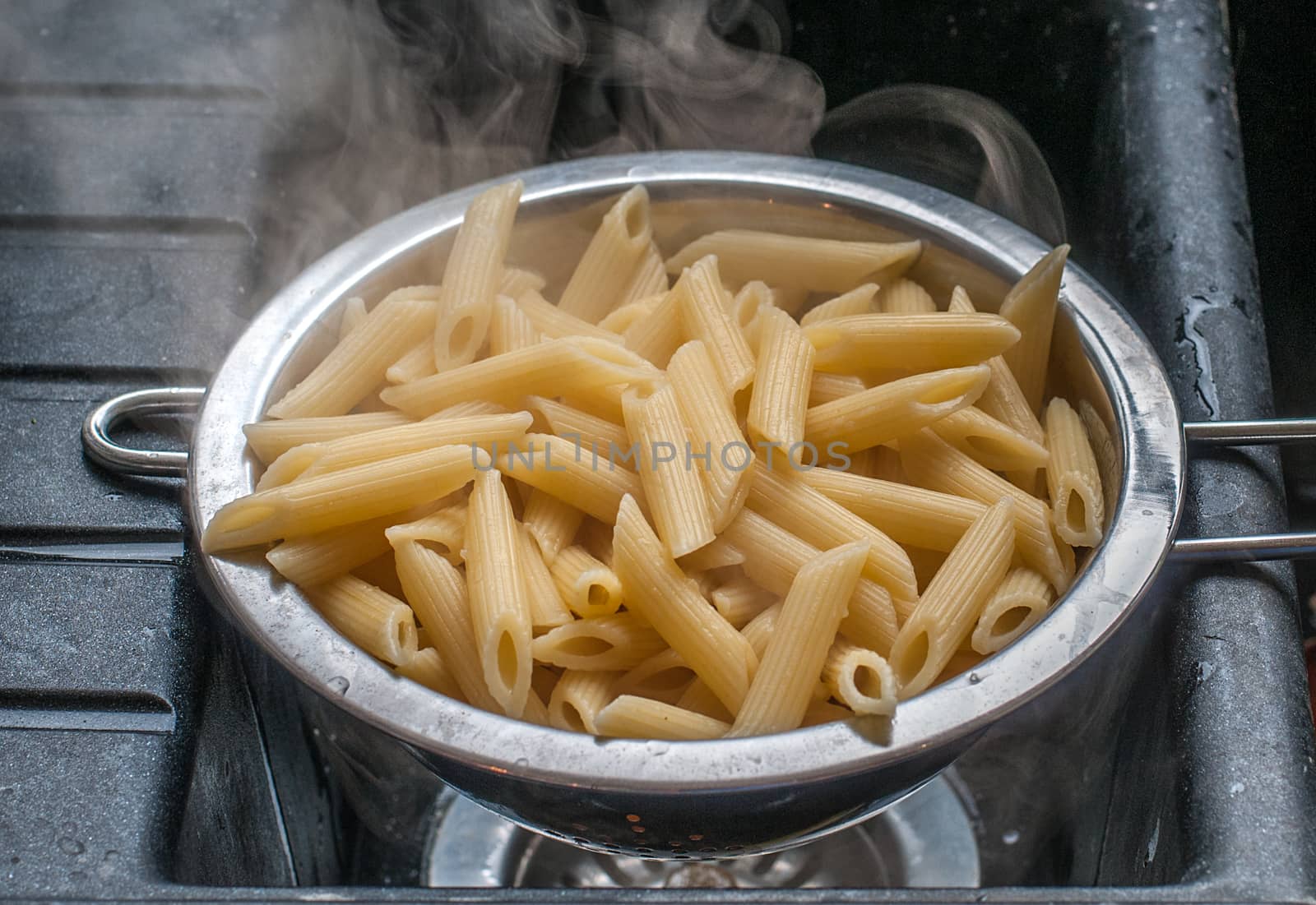 cooked penne rigate in a sieve by sirspread