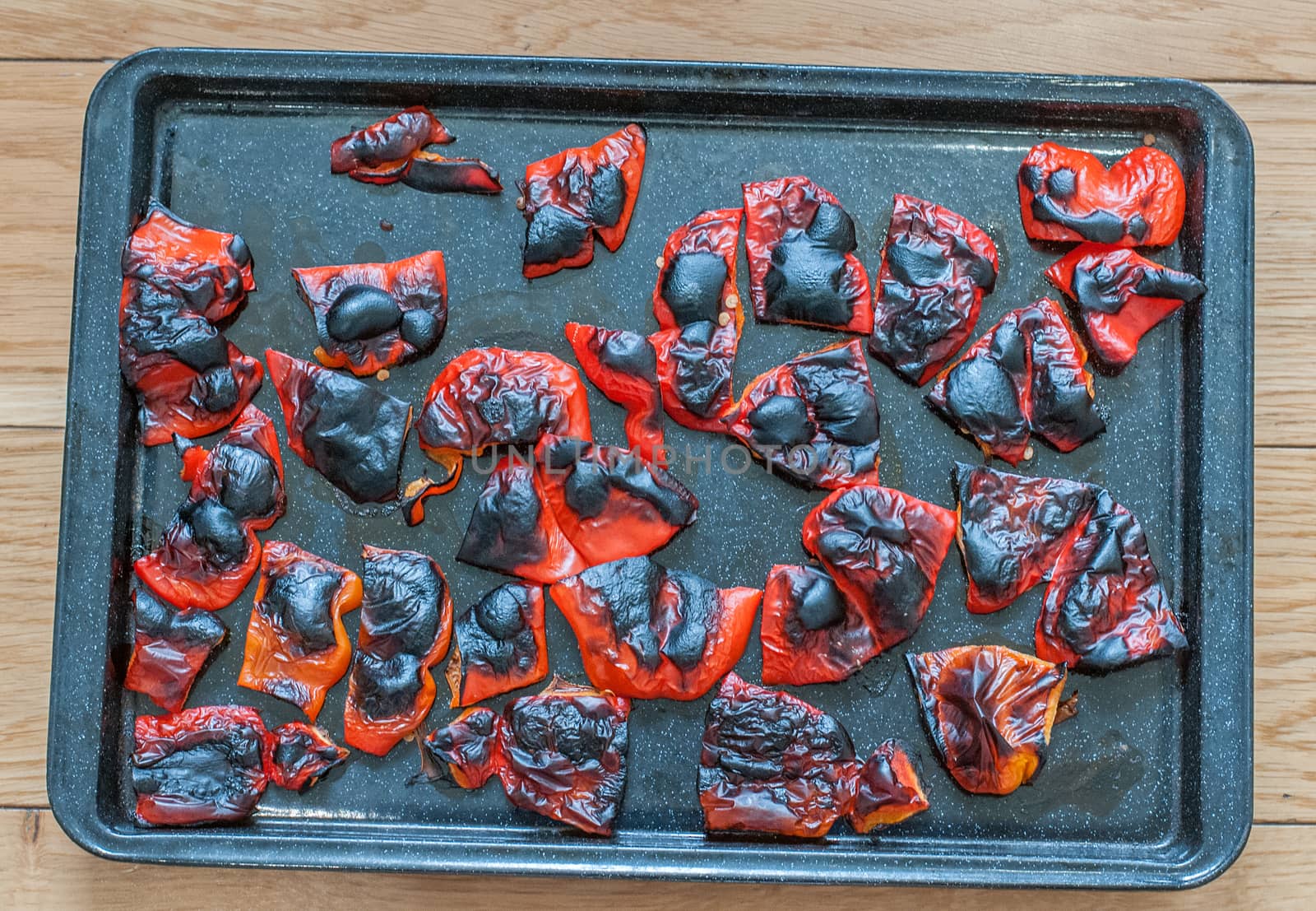 grilled red peppers blackened and blistered ready for thier skins to be removed by sirspread