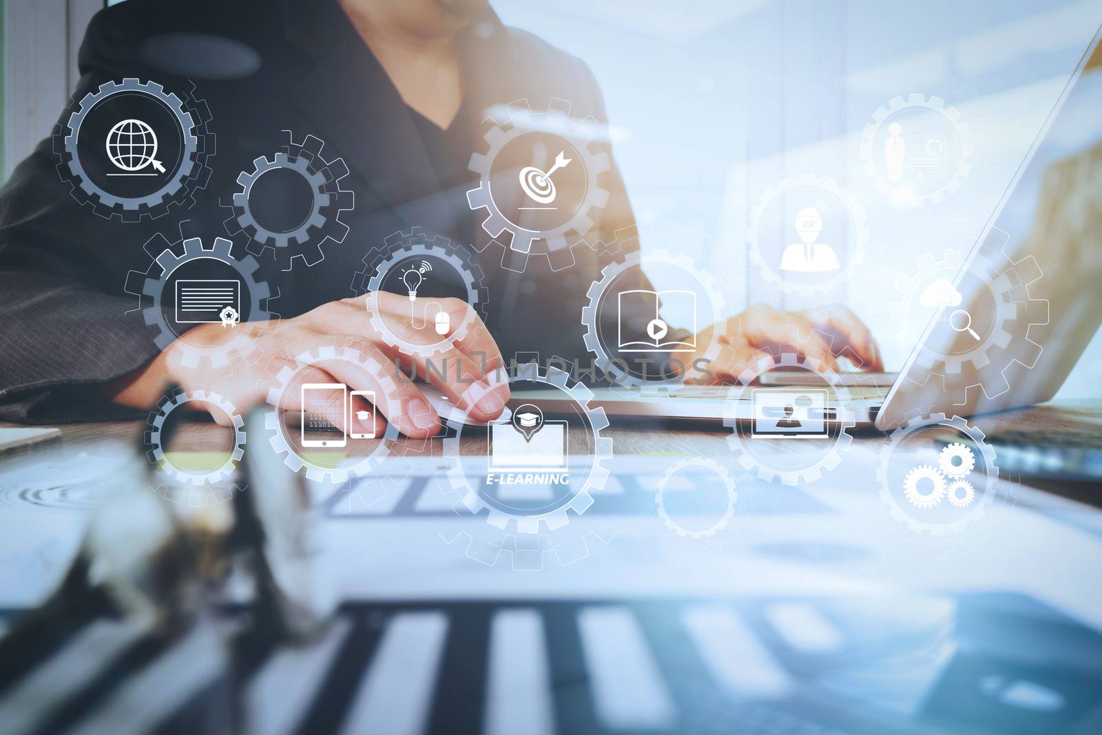 E-learning with connected gear cogs connected diagram virtual dashboard.business documents on office table with laptop computer with smart phone and graph business diagram and man working in the background