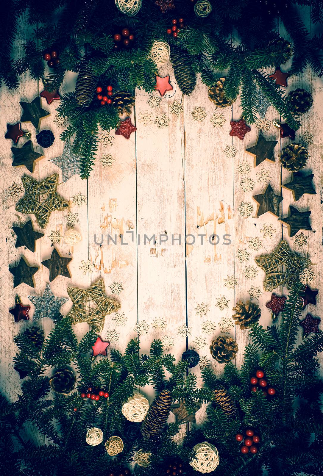 Christmas background. Frame made with fir twigs, red berries, cones and Xmas decoration on a wooden board in vintage style. Flat lay, top view, copy space. 